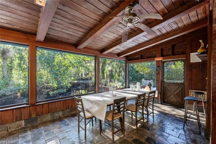 Sunroom with stone tile floors, wood walls, vaulted ceiling with beams, and wooden ceiling