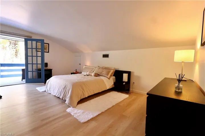 Bedroom with light wood-style floors, access to outside, and vaulted ceiling