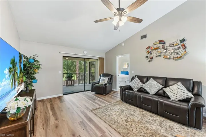 Living room with light wood-style flooring, high vaulted ceiling, and ceiling fan