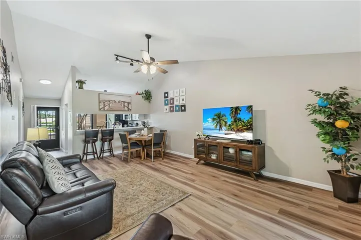 Living room featuring light wood finished floors, lofted ceiling, and ceiling fan