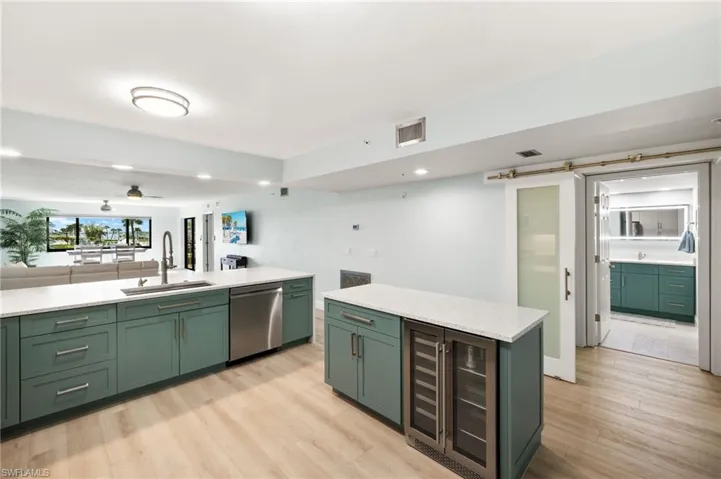 Kitchen featuring visible vents, green cabinets, light wood-style flooring, stainless steel dishwasher, and a sink
