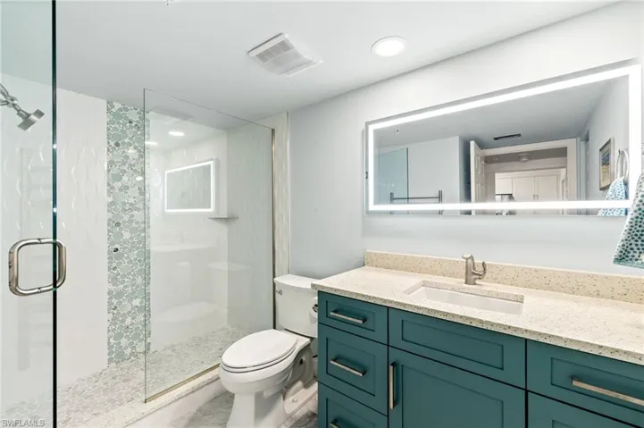 Full bathroom with visible vents, a stall shower, toilet, and vanity