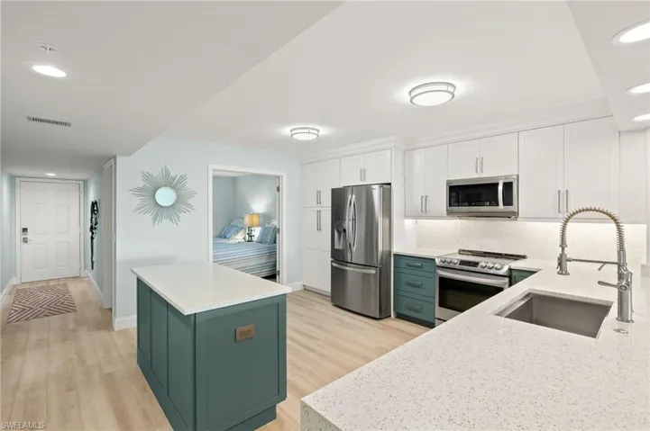 Kitchen with visible vents, green cabinets, a sink, stainless steel appliances, and white cabinetry