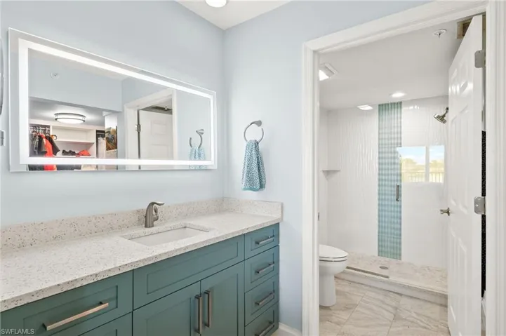 Bathroom featuring a shower stall, toilet, and vanity