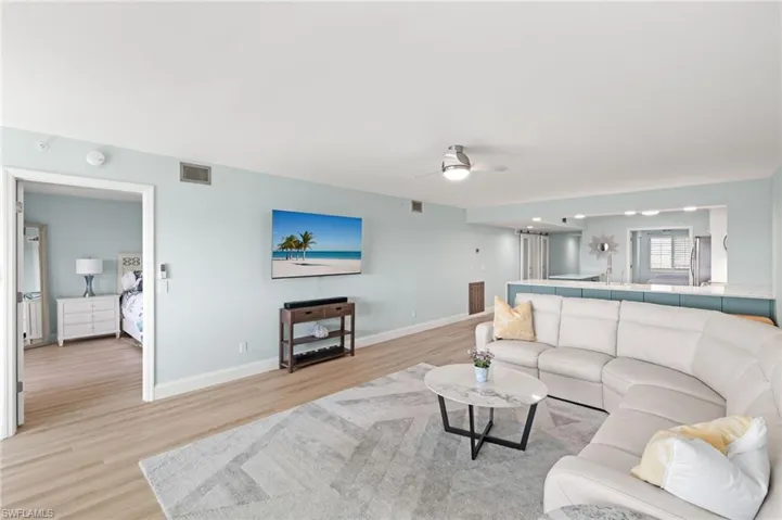Living area with baseboards, light wood-style floors, visible vents, and ceiling fan