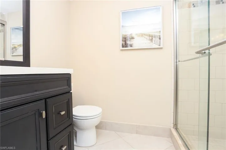Full bathroom featuring a shower stall, tile patterned floors, vanity, baseboards, and toilet
