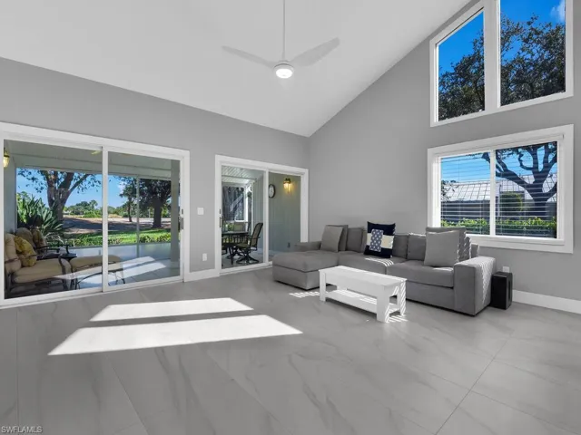 Living room featuring high vaulted ceiling, ceiling fan, marble finish floors, and a sunroom