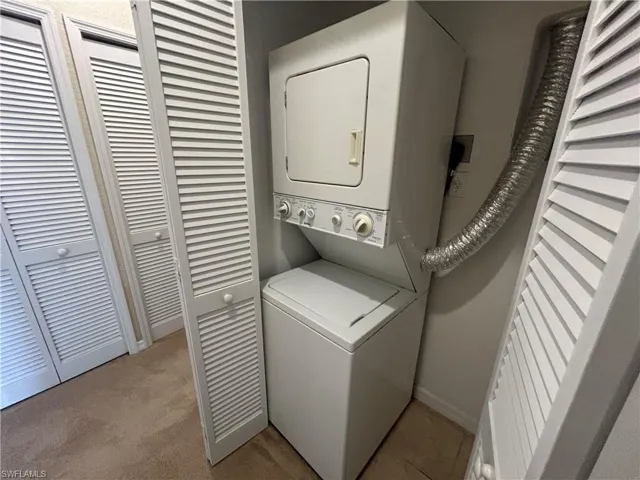 Laundry area featuring stacked washer and clothes dryer and baseboards