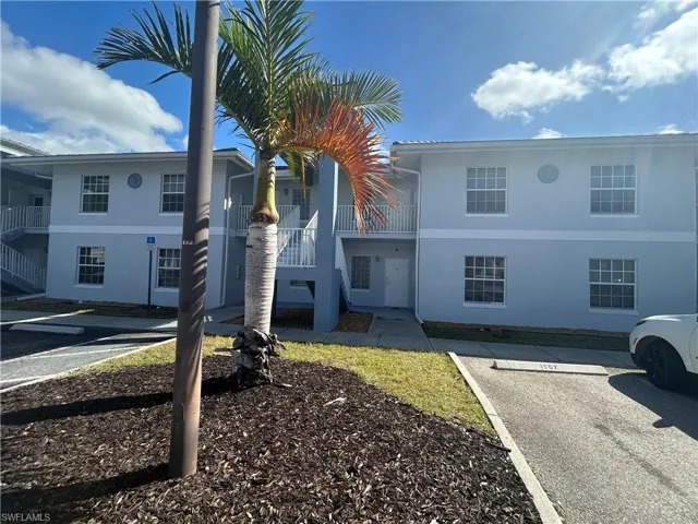View of apartment building / complex featuring uncovered parking and stairs