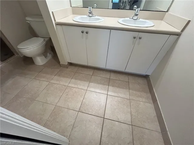 Bathroom with double vanity and light tile patterned floors