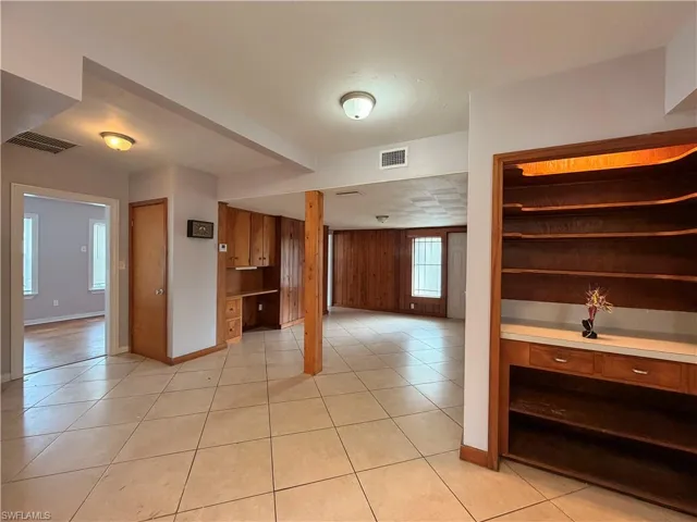 Kitchen with wooden walls, light tile patterned floors, light countertops, and open floor plan