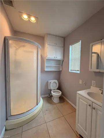 Full bath featuring a stall shower, vanity, and light tile patterned flooring