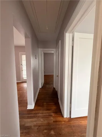 Corridor featuring attic access and dark wood-style flooring