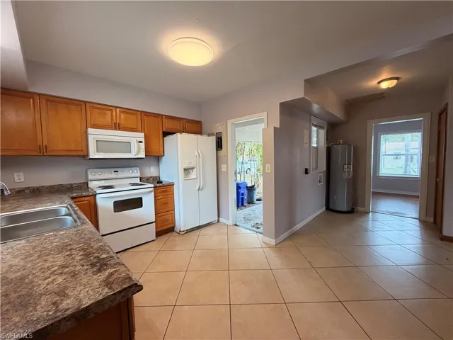 Kitchen with dark countertops, white appliances, wood finish cabinetry, and water heater