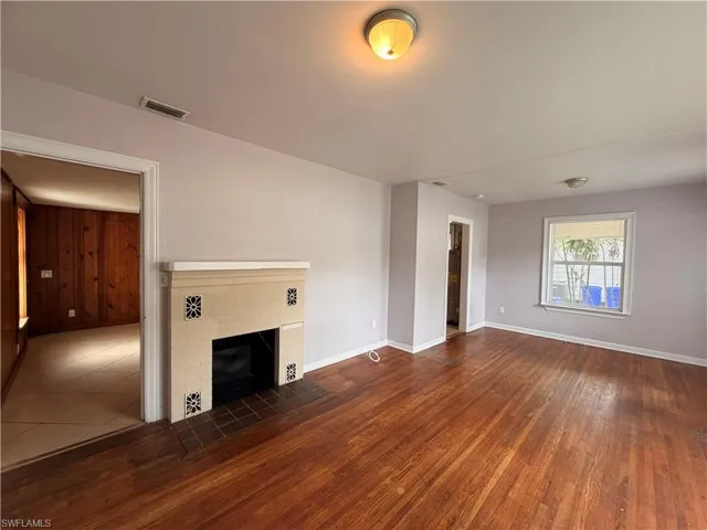Unfurnished living room with dark wood finished floors and a fireplace