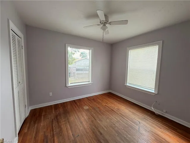 Unfurnished bedroom with a closet, dark wood-style flooring, and ceiling fan