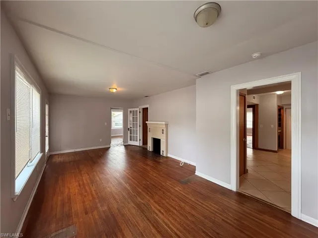 Unfurnished living room featuring dark wood-type flooring and a fireplace