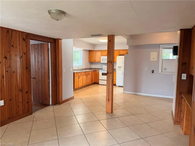 Kitchen with white appliances, wood finish cabinets, light countertops, and light tile patterned floors