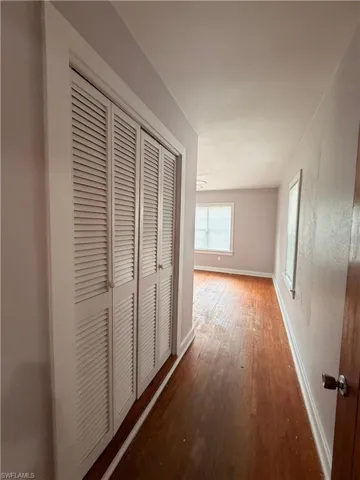 Hallway with baseboards and dark wood-style flooring