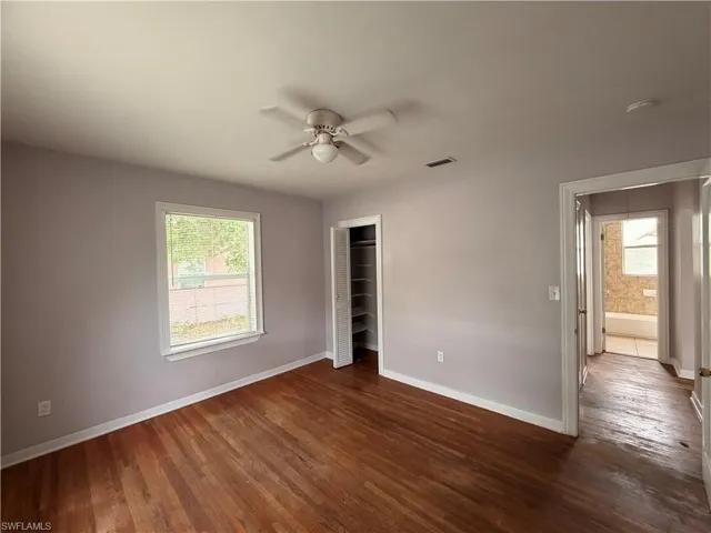 Unfurnished bedroom featuring dark wood-style flooring, a closet, and ceiling fan