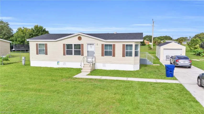 Manufactured / mobile home with a garage, a trampoline, an outbuilding, and a front yard