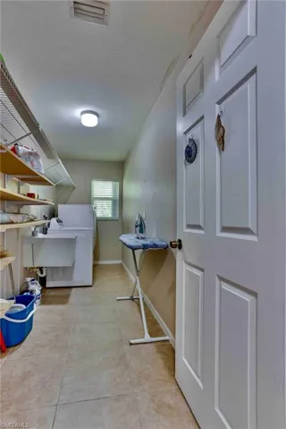 Laundry room with baseboards, light tile patterned floors, washer / dryer, and a textured ceiling