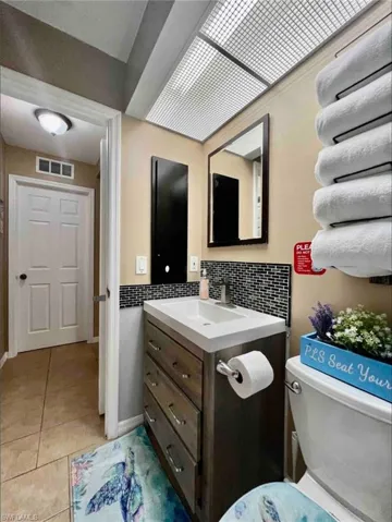 Bathroom with tile patterned flooring, decorative backsplash, toilet, and vanity