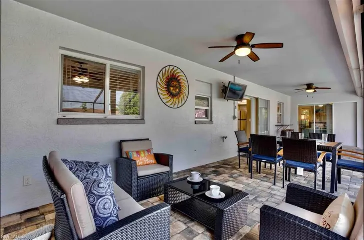 Living room featuring ceiling fan, a textured wall, and stone finish flooring