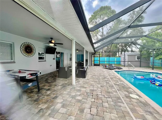 Outdoor pool featuring a storage shed, a patio area, ceiling fan, an outbuilding, and fence
