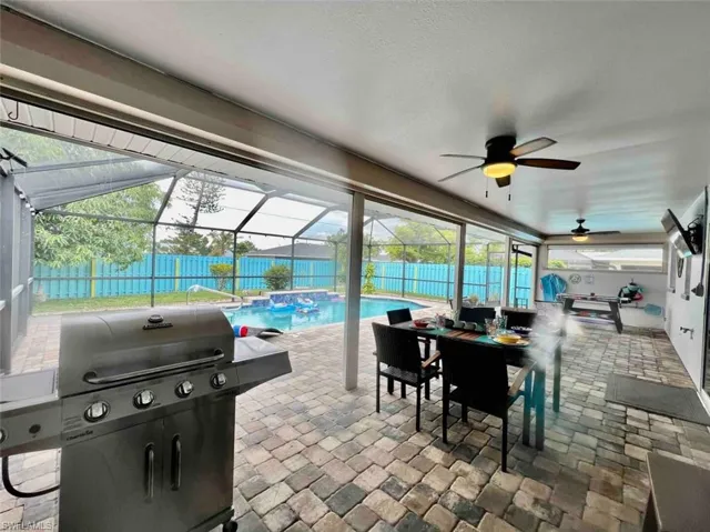 View of patio / terrace with grilling area, a fenced backyard, a ceiling fan, outdoor dining space, and a lanai