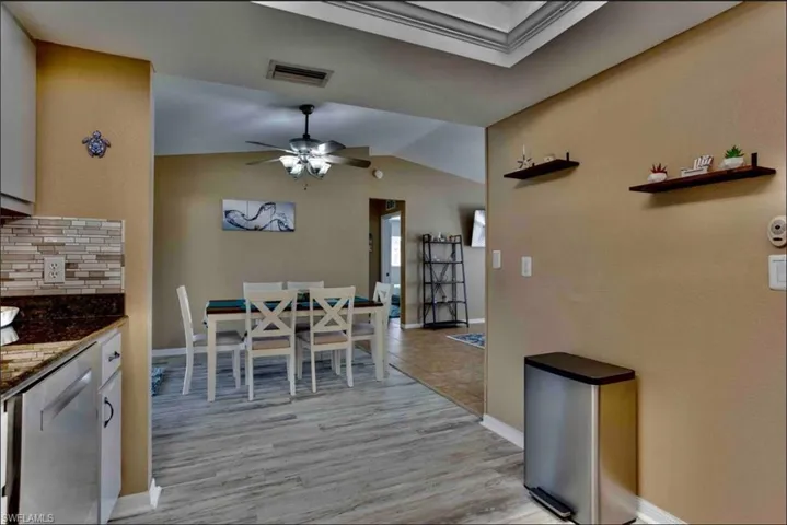 Dining space with baseboards, light wood-type flooring, a ceiling fan, and lofted ceiling