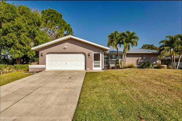 Single story home featuring a front lawn, driveway, a garage, and stucco siding