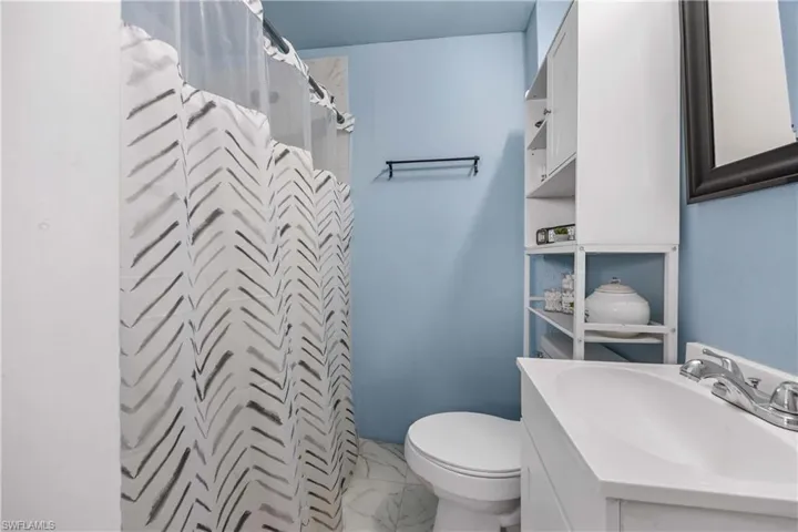 Full bath with a stall shower, vanity, and light marble finish floors