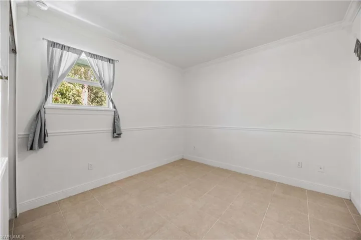 Spare room with ornamental molding and baseboards