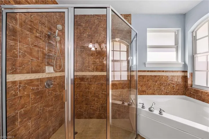 Full bath with a stall shower, a bath, and a wainscoted wall