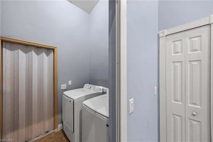 Laundry area featuring washer and clothes dryer and dark tile patterned floors