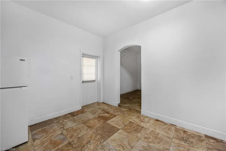 Unfurnished room with arched walkways and light stone finish flooring