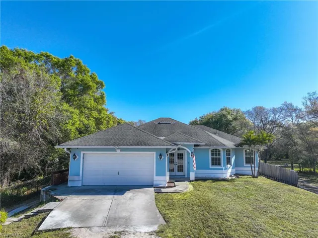 Single story home featuring an attached garage, driveway, stucco siding, french doors, and a shingled roof