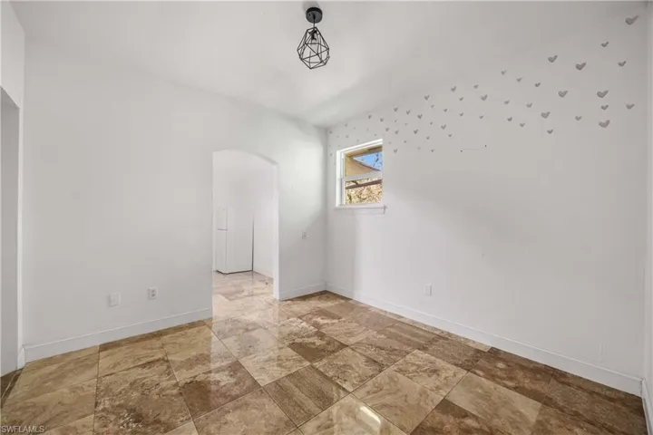 Spare room featuring arched walkways and light stone finish floors