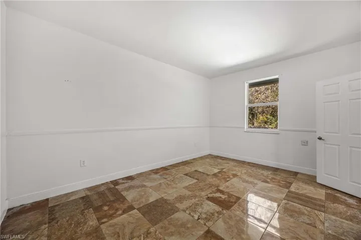 Unfurnished room with light stone finish floors