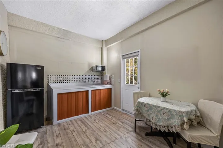 Kitchen featuring freestanding refrigerator, a textured ceiling, light wood-style floors, tasteful backsplash, and wood finish cabinetry