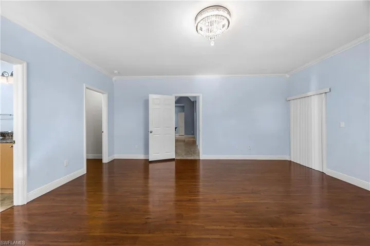 Unfurnished living room with dark wood-style floors and crown molding