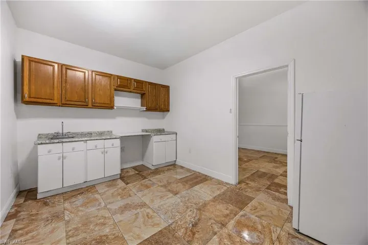 Kitchen with freestanding refrigerator, light countertops, wood finish cabinetry, and lofted ceiling