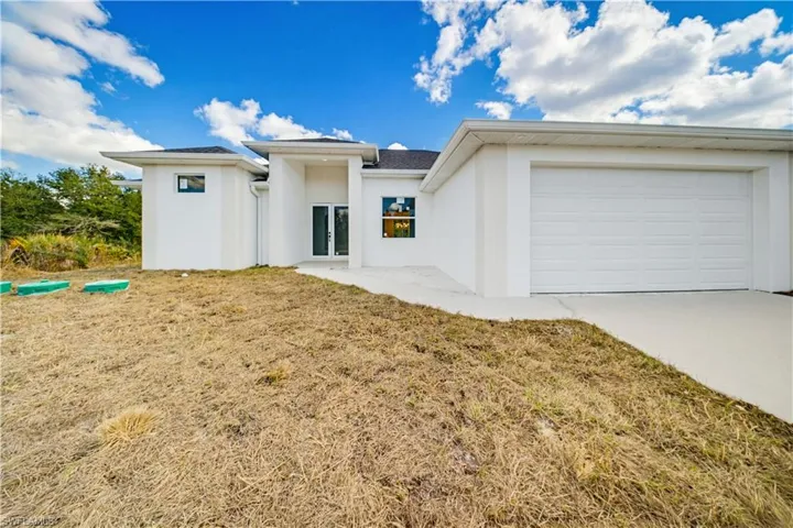 View of front of house featuring french doors, stucco siding, concrete driveway, and an attached garage