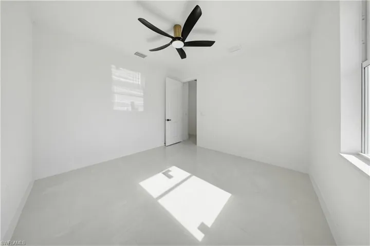 Unfurnished bedroom with ceiling fan and multiple windows