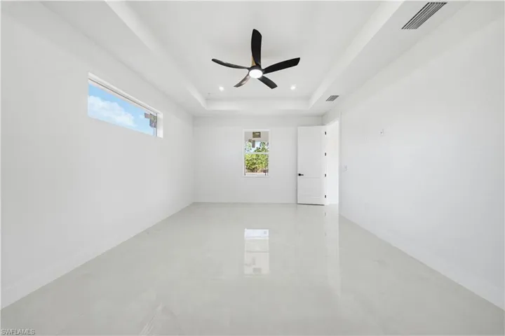 Spare room with a tray ceiling, ceiling fan, and recessed lighting