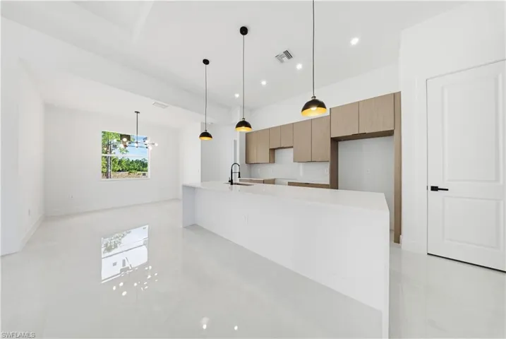 Kitchen featuring modern cabinets, light stone counters, decorative light fixtures, a chandelier, and recessed lighting