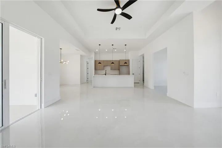 Unfurnished living room featuring a raised ceiling, a chandelier, and a ceiling fan