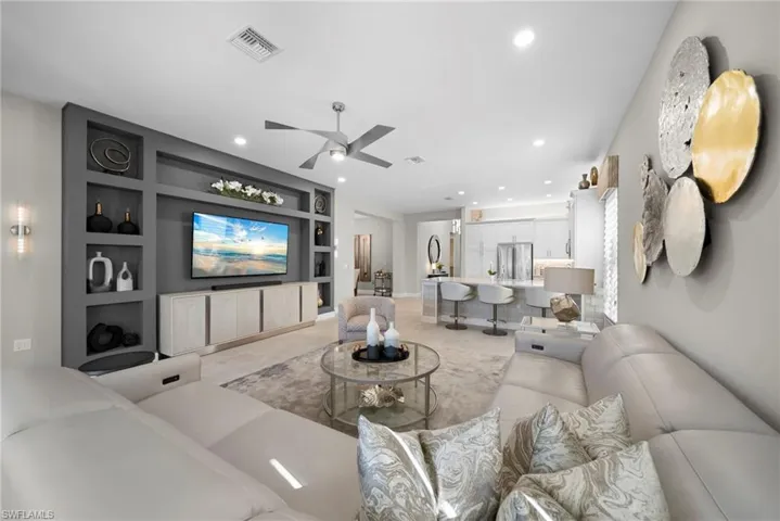 Living room with built in shelves, a ceiling fan, and recessed lighting