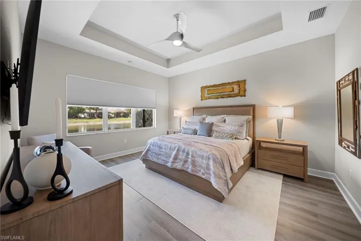 Bedroom featuring a raised ceiling, ceiling fan, and wood finished floors